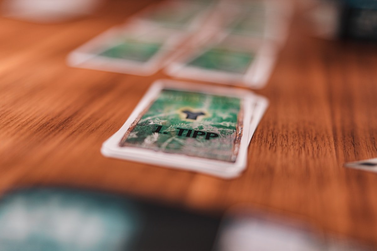Cartes de jeu de poker vertes avec le mot "Tipp" imprimé dessus, posées sur une surface en bois.