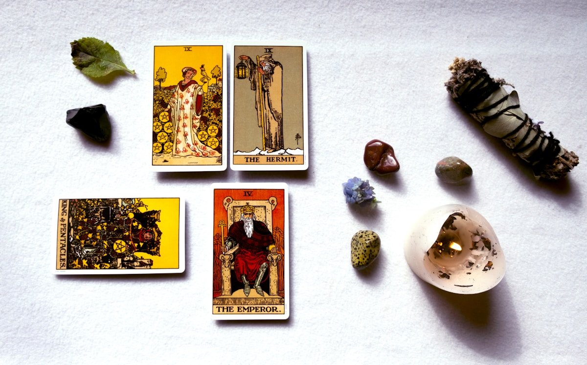 Cartes de tarot, cristaux, feuille et bâton de sauge sur fond blanc.