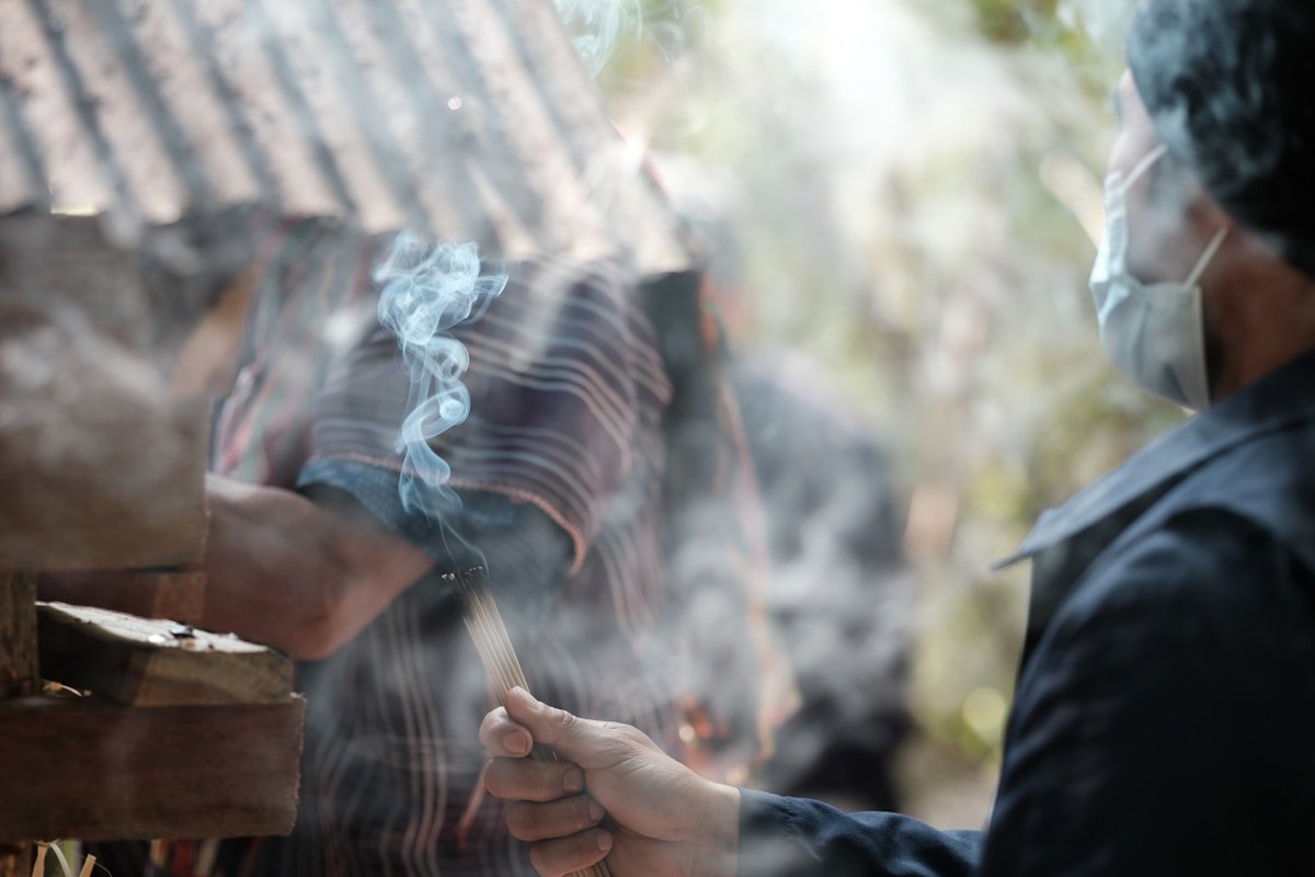 Personne fumant une cigarette dans un environnement forestier.