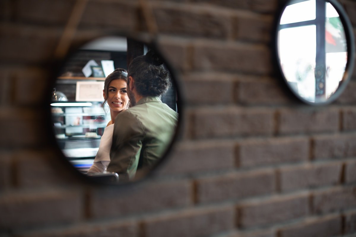 Couple enlacé dans un miroir, souriant dans une pièce rustique.