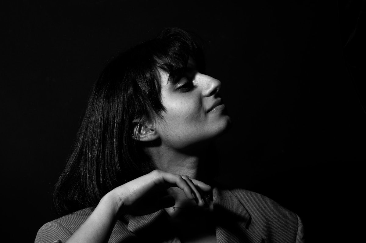 Femme aux cheveux noirs, portrait en noir et blanc, expression pensive.