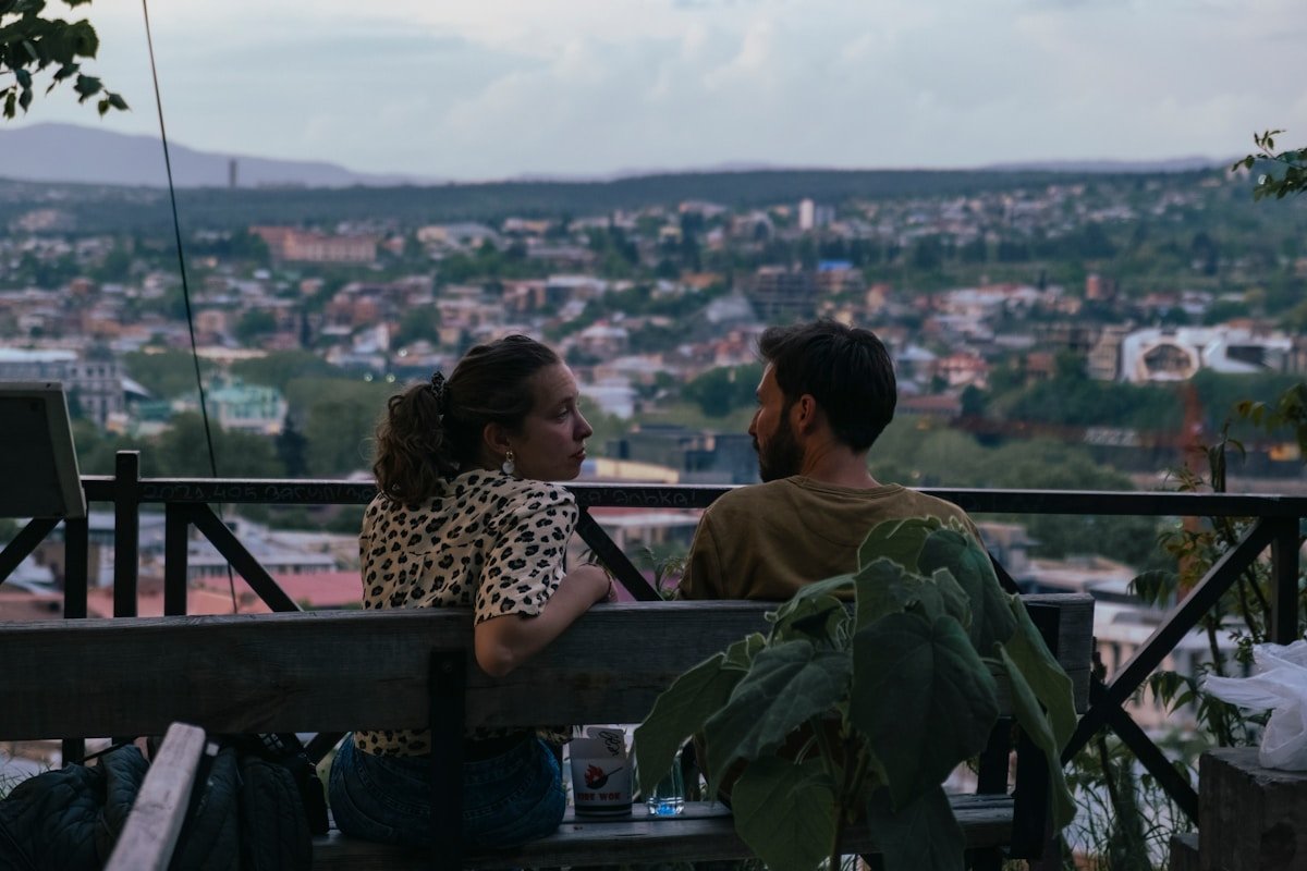 a man and woman sitting on a balcony overlooking a city