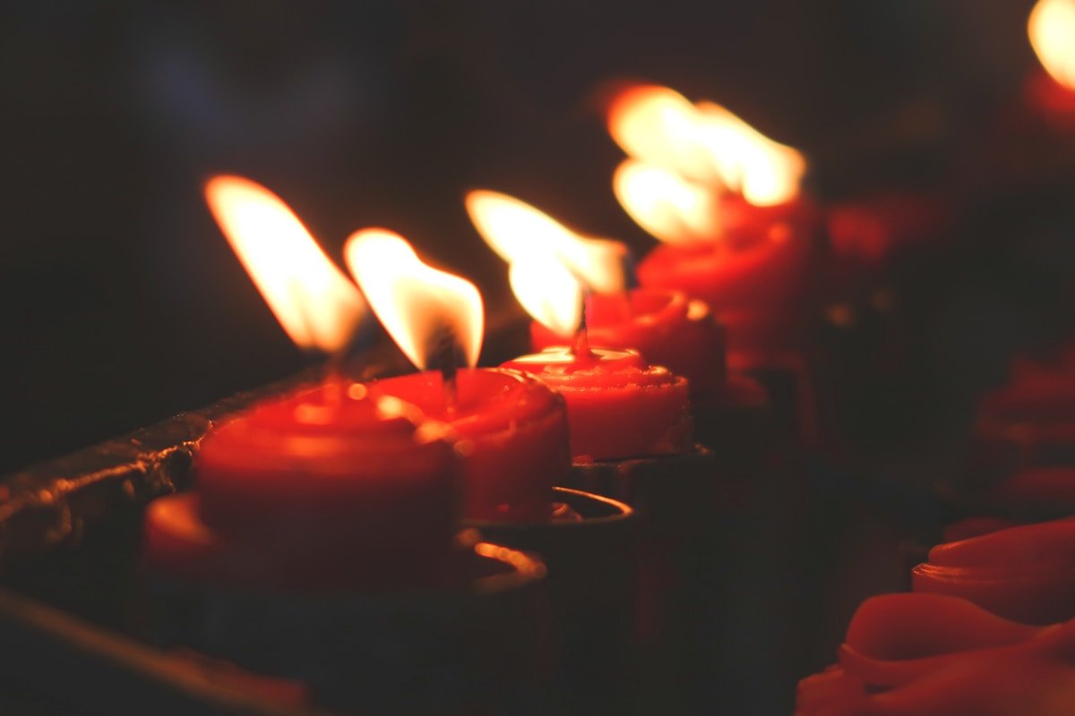 Bougies rouges allumées dans l'obscurité, lueur chaude et mystérieuse.
