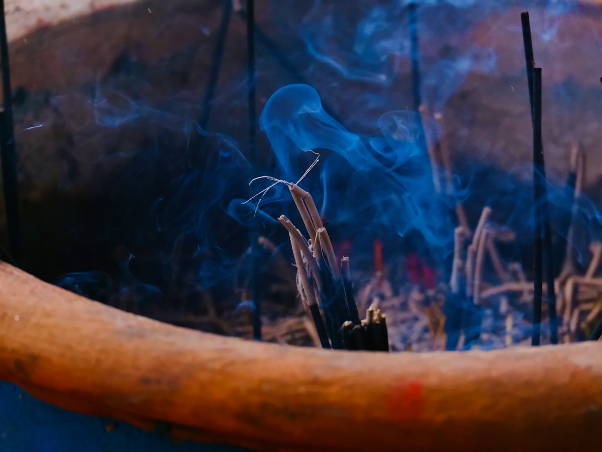 Bâtons d'encens fumants dans une atmosphère mystique et colorée.