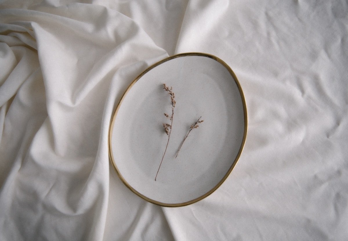 Cadre doré avec plante séchée délicatement disposée.