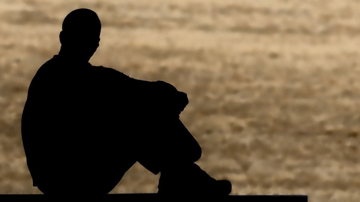 A silhouette of a man sits alone.