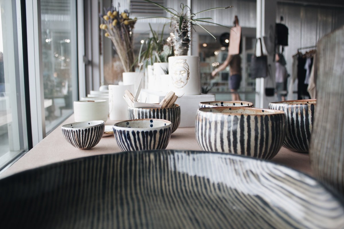 Céramiques artisanales aux motifs rayés, fleurs séchées, vitrine de boutique.