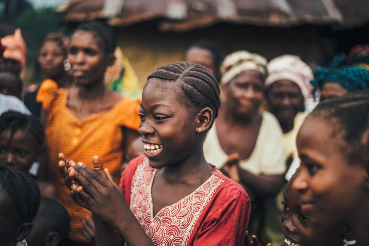 Groupe de personnes africaines souriantes dans un village rural.