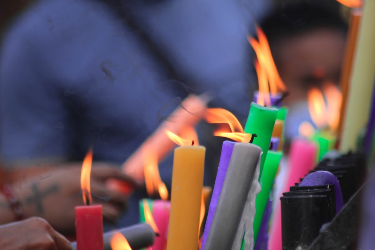 Bougies colorées allumées dans une atmosphère sombre et mystique.