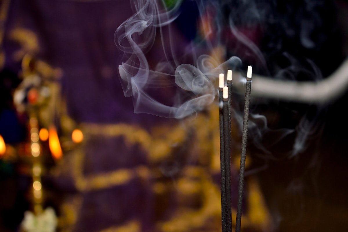 Bâtons d'encens fumants dans une atmosphère sombre et mystique.