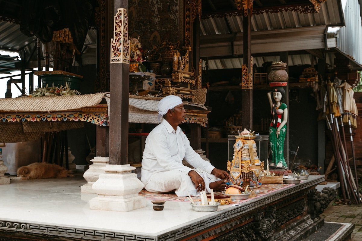 Homme en tenue blanche effectuant une cérémonie religieuse dans un temple orné.