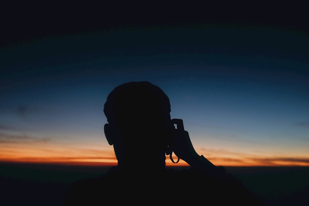Silhouette d'une personne photographiant un coucher de soleil.