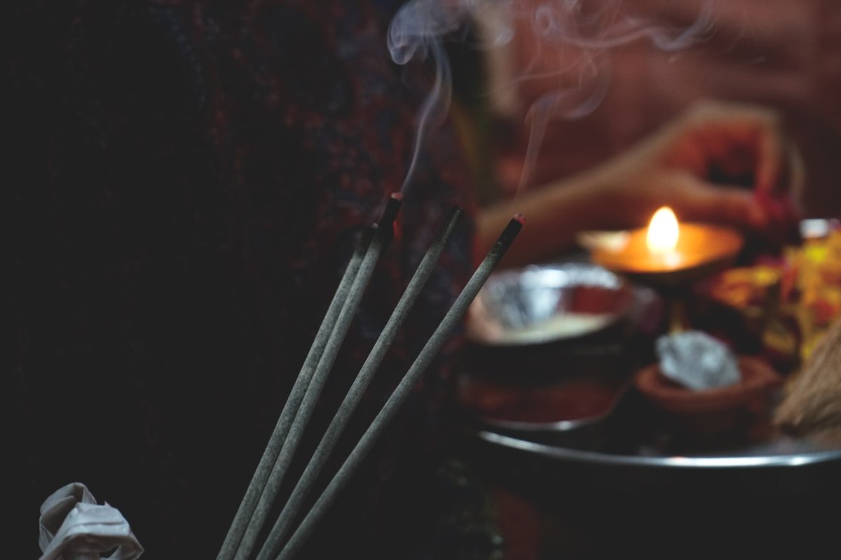 Bâtons d'encens fumants, bougie allumée, objets religieux.