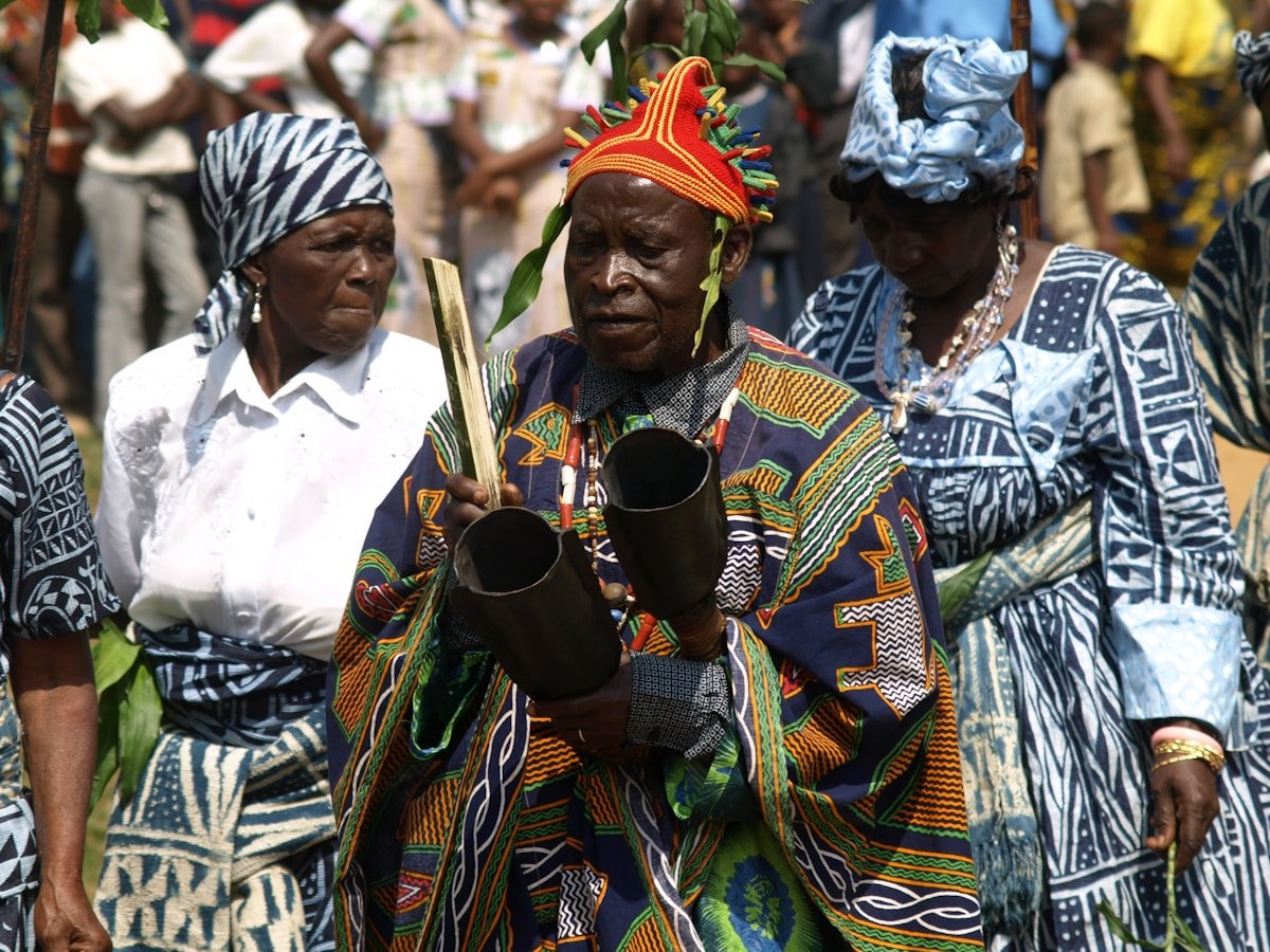 Hommes africains en costumes traditionnels colorés et ornés.