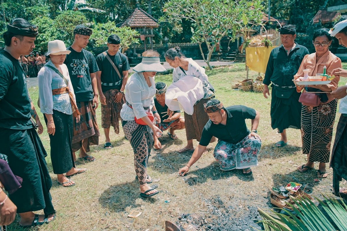 Groupe de personnes en tenue traditionnelle balinaise dans un jardin verdoyant.