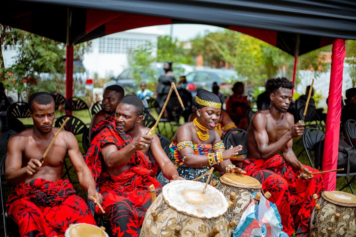 Groupe d'hommes africains en costumes traditionnels jouant des tambours et des instruments.