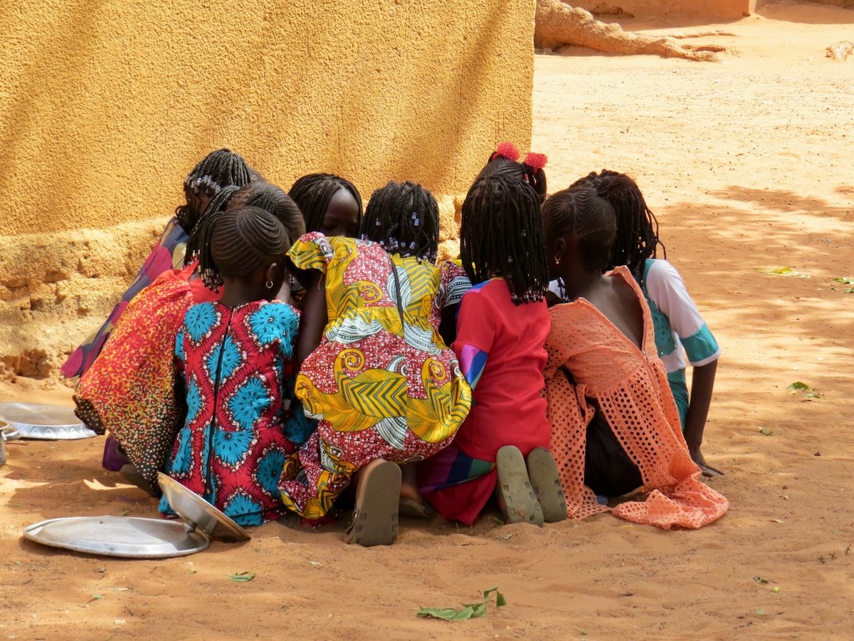 Groupe de femmes africaines en vêtements colorés, assises ensemble.