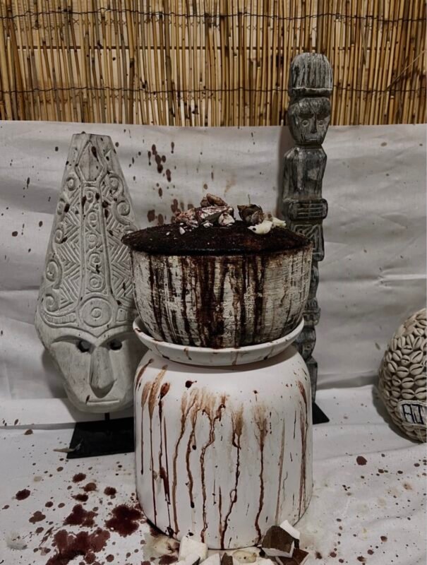 Statues et pot rituel devant un mur de paille